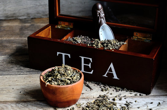 A collection of varieties of tea in a special tea box, a special ceramic spoon and wooden utensils.