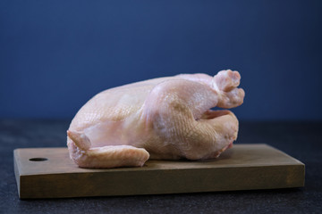 Chicken prepared for cooking on a wooden board.