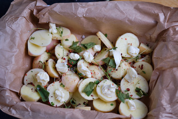Cushion of potatoes for chicken. The process of cooking chicken with herbs, spices and lemon in the oven. On the table are the products that are needed for cooking. The hands of the cook in the frame.