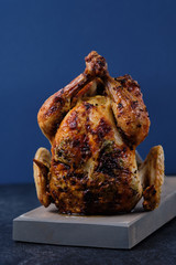 Oven baked chicken with spices, herbs and lemon on a wooden board with a beautiful golden brown crust.