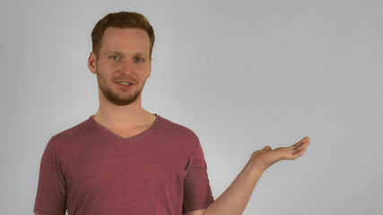 casual redhead man showing your products on hand. redheaded caucasian men with smile wearing in shirt looking at the camera represent something