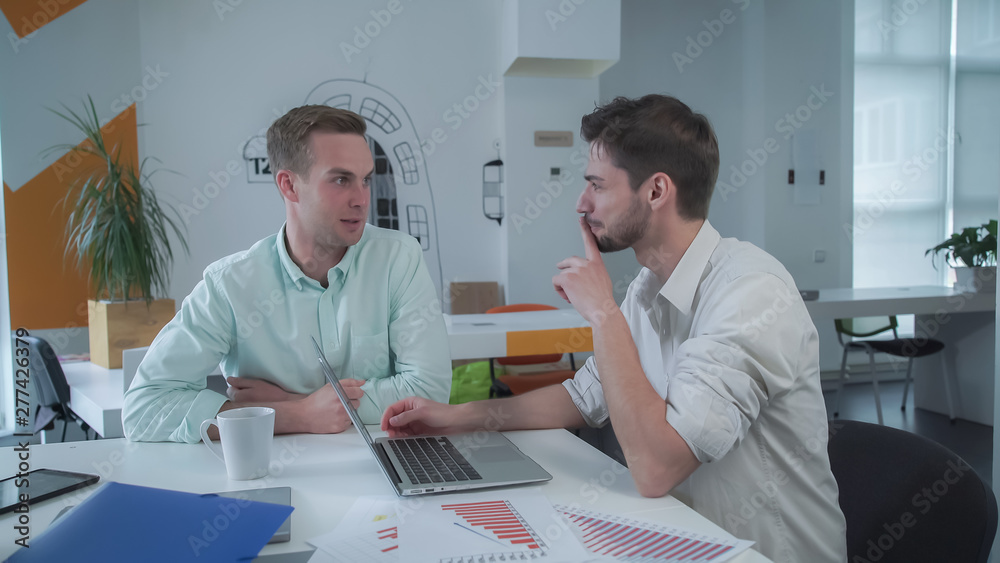 Poster men have fun at the working place. cheerful happycolleagues laughing in the modern open space room. 