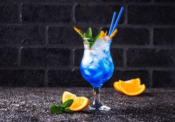 Blue cocktail drink with ice and orange