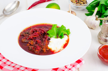 Borsch on red napkin on white wooden background