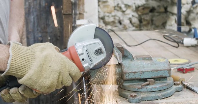 D&eacute;coupe d'une pi&egrave;ce m&eacute;tallique avec une disqueuse dans un attelier 