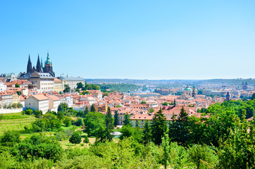 Fototapeta na wymiar Amazing cityscape of Prague, Czech Republic captured from the Petrin hill with adjacent green park. The dominant of the Czech capital is gorgeous Prague Castle and Saint Vitus Cathedral. Skyline