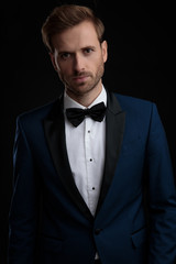 Serious looking groom posing while wearing a blue tuxedo