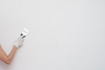 Working tool, spatula in hand against the background of a white wall, work plasterer. Putty walls with their own hands.