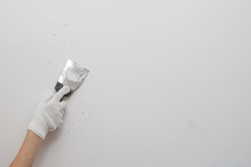 Working tool, spatula in hand against the background of a white wall, work plasterer. Putty walls...