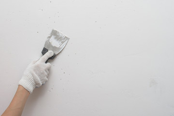 Working tool, spatula in hand against the background of a white wall, work plasterer. Putty walls...