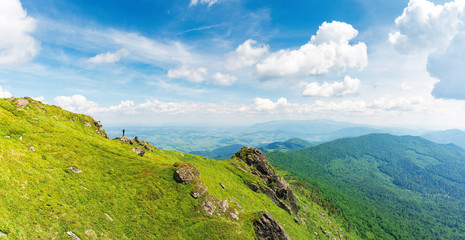 rock on the edge of a hill. view in to the valley. beautiful summer landscape of carpathian mountains. grass on the slope beneath a cloudy sky. borzhava ridge on the horizon, location mnt. pikui, UA