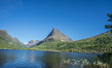 Naklejka na ściany i meble Panoramic view over the lake at Innerdalstarnet (also called Dalatarnet) peak - a 1,452-metre (4,764 ft) sharp pyramidical mountain in the Sunndalen valley. It is called Norwegian Matternhorn. Norway.