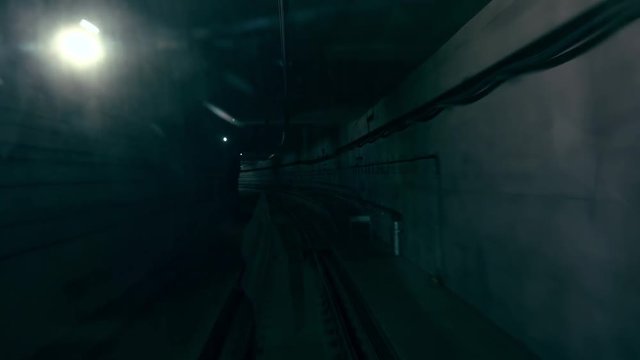 Front window view of train moving along gloomy metro or subway railroad tunnel or underground passage. Modern electric rapid transport, urban mass transit railway system or MTR. Public transportation.