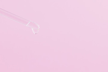 Serum for cosmetic procedures. Serum on a pink background. Cosmetic pipette with a drop. Minimalism. Close up