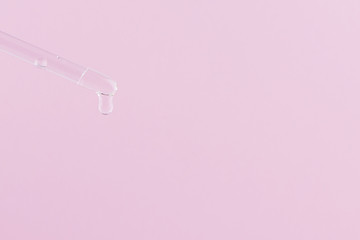 Serum for cosmetic procedures. Serum on a pink background. Cosmetic pipette with a drop. Minimalism. Close up