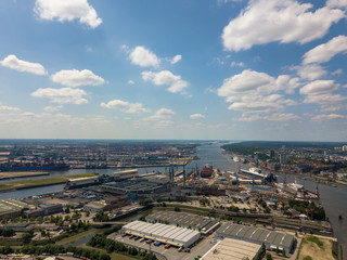 Aerial drone photo over shipyard and warehouses towards the container harbor with crane machinery and container ships in Hamburg, Germany