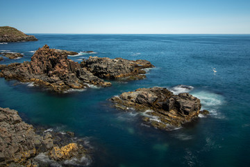 Crystal clear pristine blue water surrounded by a rugged rocky coastline. Elliston, Newfoundland Canada.  
