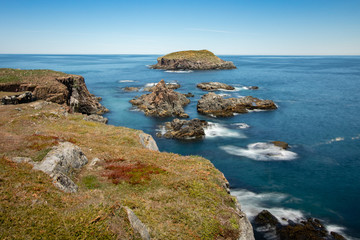 Fototapeta na wymiar Crystal clear pristine blue water surrounded by a rugged rocky coastline. Elliston, Newfoundland Canada. 