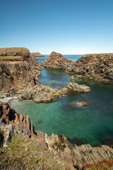 Crystal clear pristine blue turquoise water surrounded by a rugged rocky coastline. Elliston, Newfoundland Canada.  