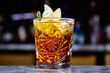Cocktail with cognac in a glass of old fashion on the bar.