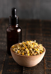 Chamomile Oil with Dried Chamomile Flowers on a Wooden Table