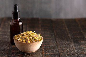 Chamomile Oil with Dried Chamomile Flowers on a Wooden Table