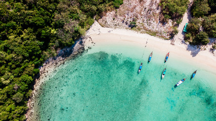 Tropical beach with longtail boats in Thailand. Crystal clear water. Drone view