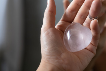 Woman holding in hand rose quartz heart shaped crystal