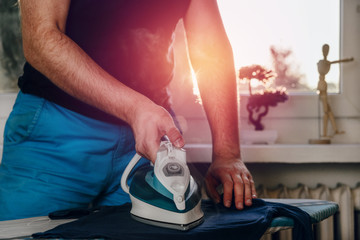 Man is ironing clothes. The concept of caring for the home, helping men in household chores. The...