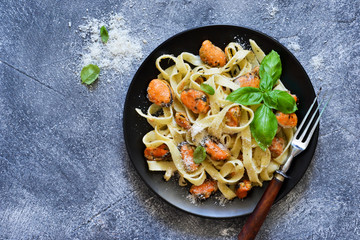 Pasta with cream sauce, mussels and parmesan on a concrete background.