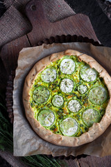 Homemade courgette and goat cheese pie on a dark rustic wooden board background
