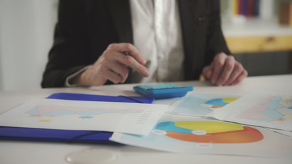 A man looks at the charts and checks them using a calculator. UHD