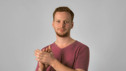 caucasian guy with red hair applauds. handsome redheaded men wearing in casual t-shirt. Portrait ginger young caucasian man clapping hands on grey background