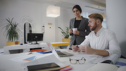 Two employees working in the office. Sit and use digital tablet and phone