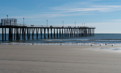 Fishing Pier Over Calm Ocean with Seagulls at Low Tide