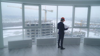 architect holding a design plan or other technical drawing looking on the project . worker in...