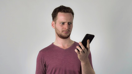 Young caucasian man has unpleasant phone conversation. angry men shouting at interlocutor. Enraged person using smartphone