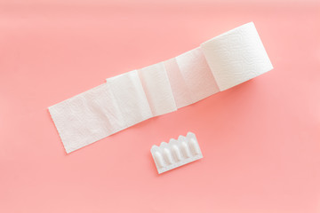Proctology concept with toilet paper roll and rectal suppository on pink background top view
