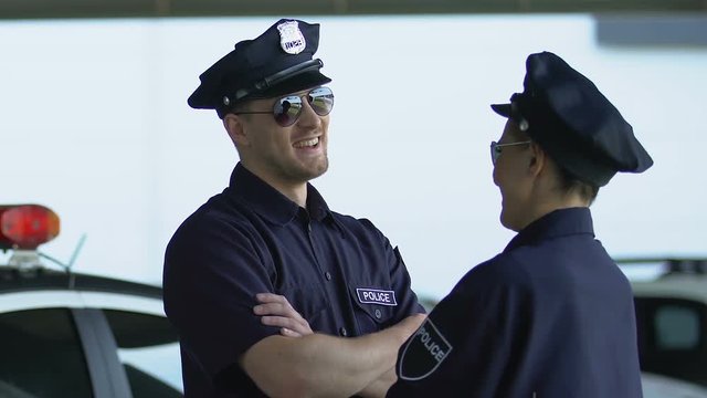Smiling police colleagues giving high-five, patrol together, security confidence
