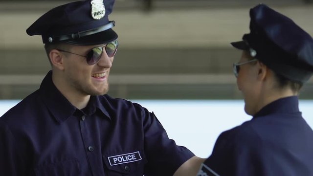Police officers in sunglasses talking and laughing, partners patrolling together