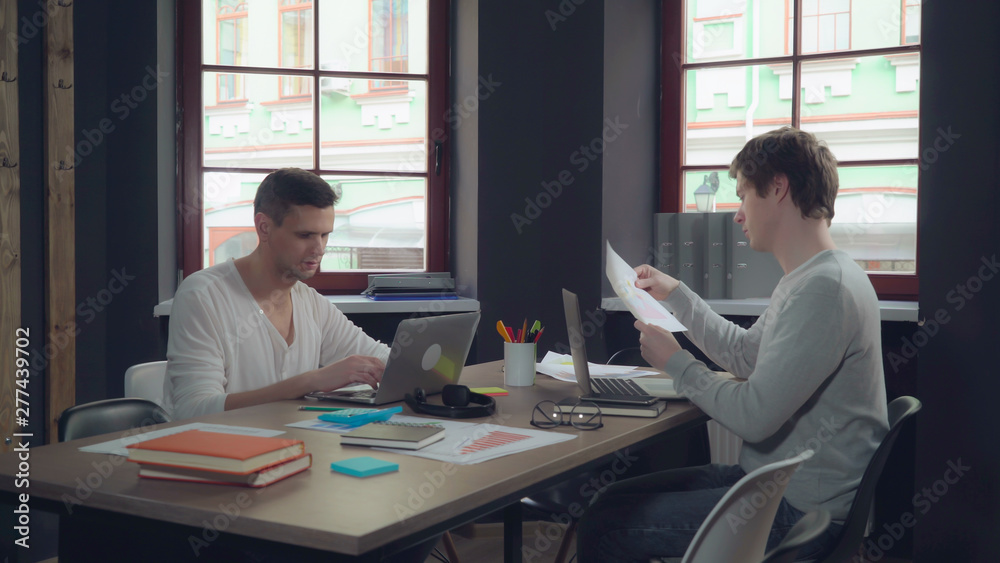 Poster young professional start up team working in modern office. caucasian men computing on laptop and dis