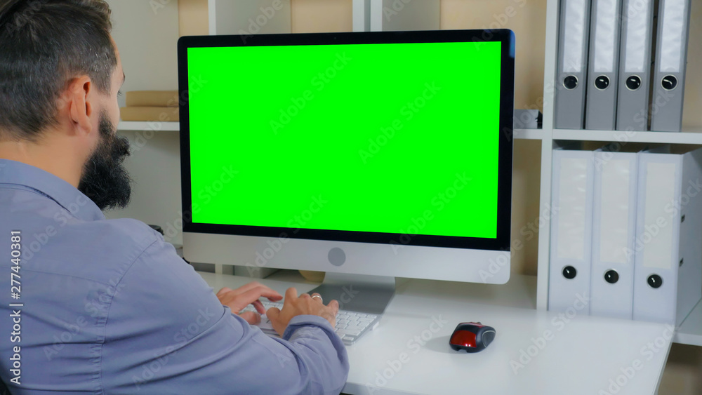 Aufkleber businessman sitting at workplace in small office. man with beard looking on display computer with gr