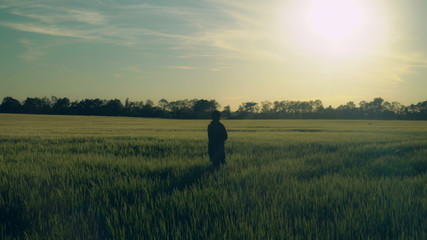 Rear back view woman walks the field. Female at the countryside enjoy freedom and nature. Beautiful...