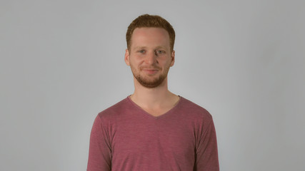 successful caucasian guy with red hair nodding approvingly. handsome redheaded men wearing in casual t-shirt. Portrait ginger young caucasian man on grey background