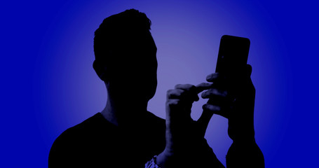 Silhouette of a male using his smartphone on a digital blue background