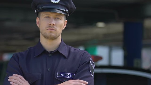 Respectable policeman in hat looking into camera, policing of city districts