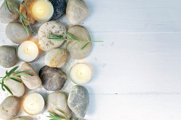 Top view SPA concept. Sea pebbles, bamboo shoots, scented candles, sea salt on a light wooden background. Copy space