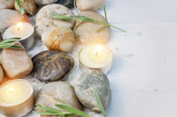 Fototapeta na wymiar SPA composition. Sea pebbles, bamboo shoots, scented candles, sea salt on a light wooden background. Copy space