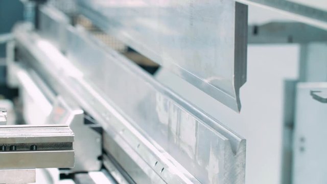 Plant worker taking finished product from machine for bending metal