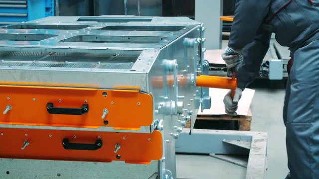 Workman working with T-shape wrench during assembly of industrial machine